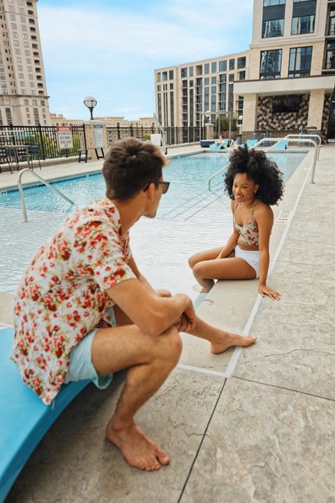 Stock photo of a two people sitting on the edge of the pool