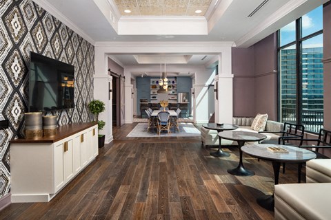 A lounge with a  few chairs that is facing a mounted television on the wall