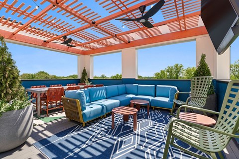 A patio with a blue couch and a red ceiling fan.