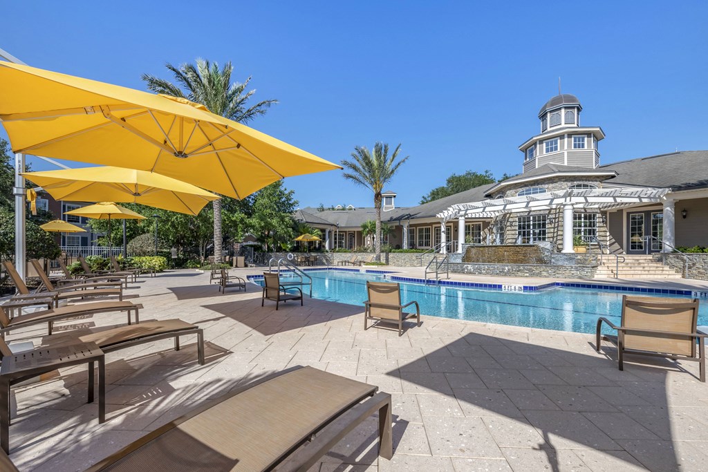 exterior swimming pool with yellow umbrellas and a white building in the background