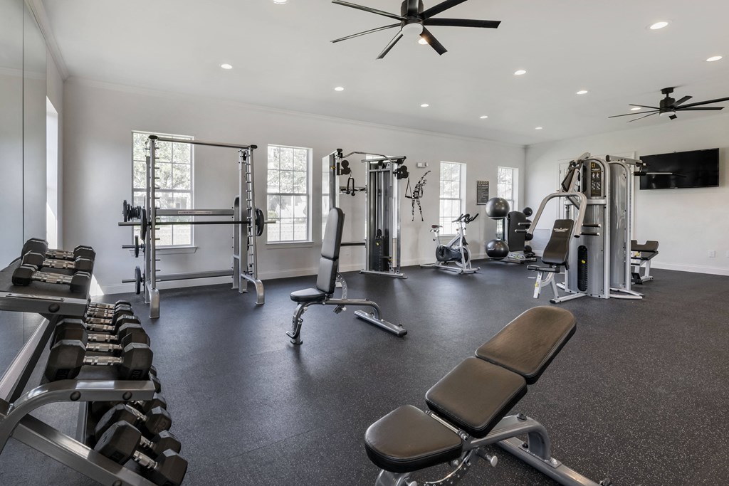 a large fitness room with exercise equipment and a flat screen tv