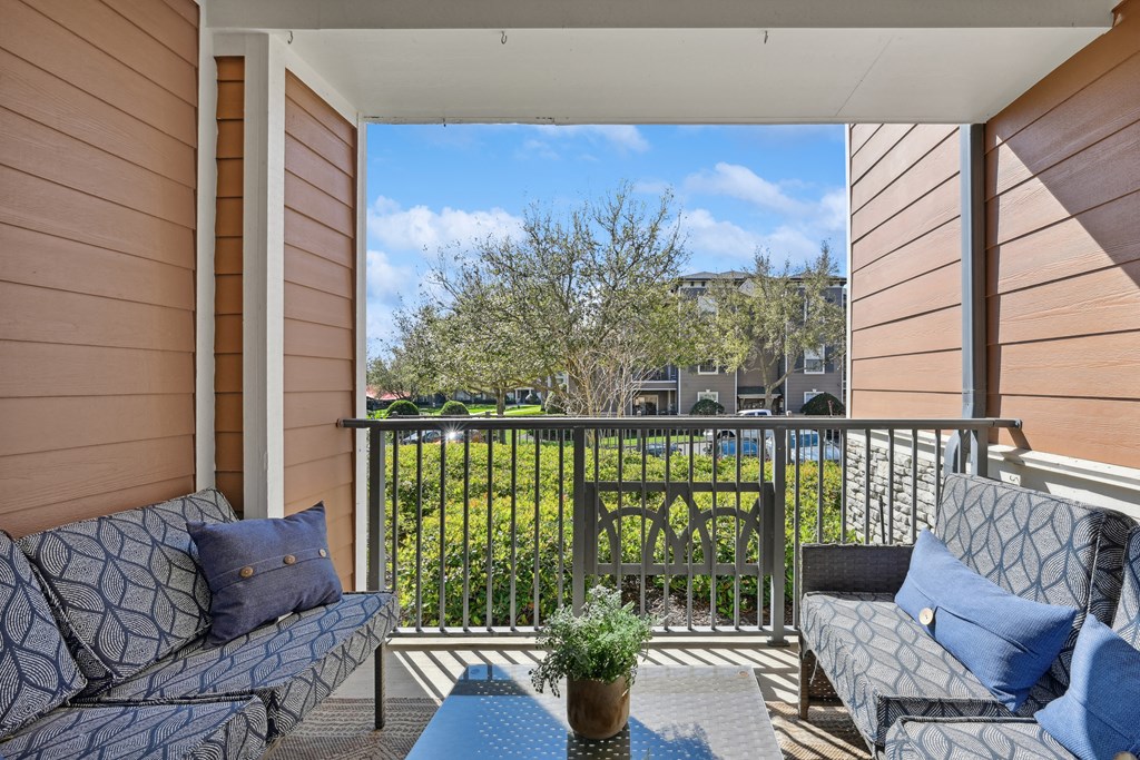 a balcony with two couches and a table and a fence
