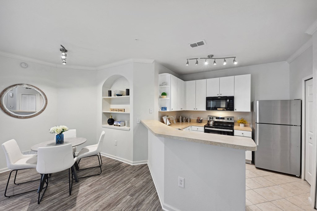 an open kitchen and dining area with a table and chairs and a refrigerator