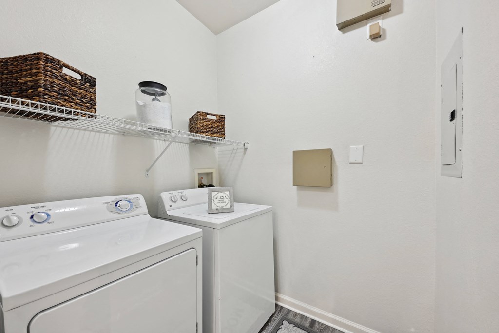 a white laundry room with a washer and dryer and a shelf above it