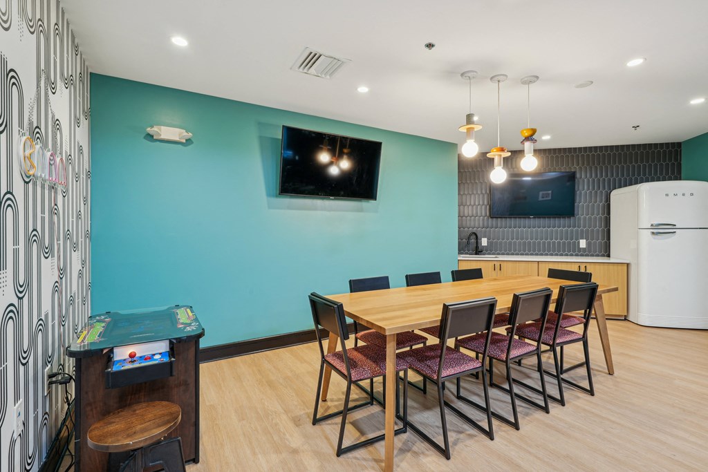 a dining room with a wooden table and chairs and a blue wall with a television