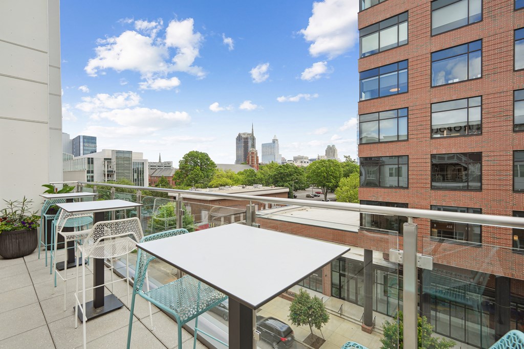 a rooftop patio with tables and chairs and a city in the background