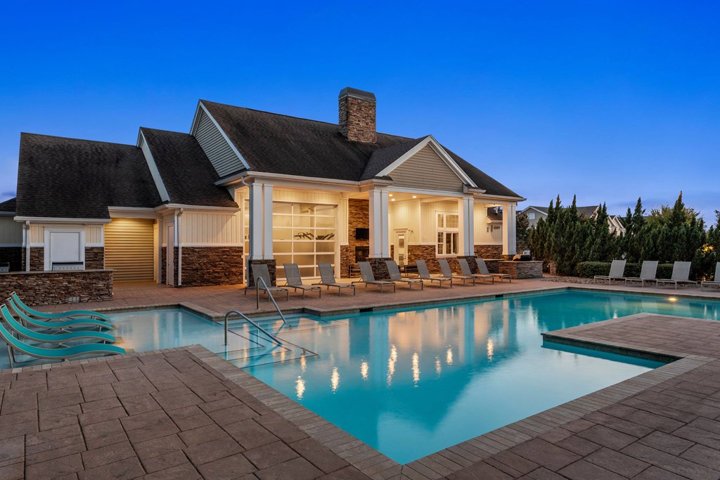 a house with a pool and chairs in front of it