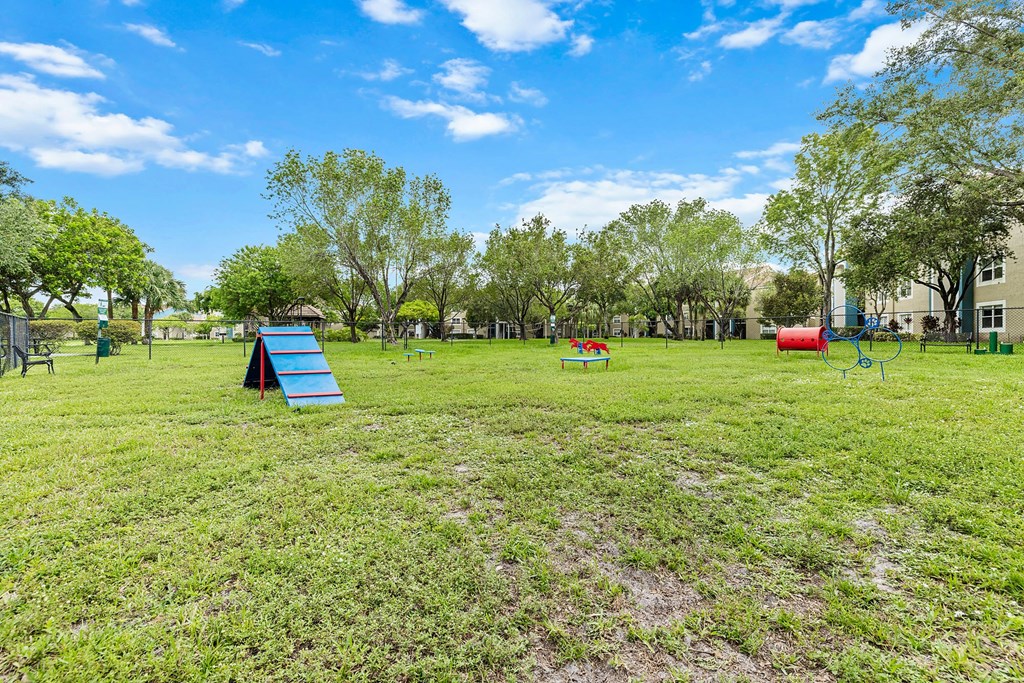 A grass area with a blue slide, red slide, and green slide.