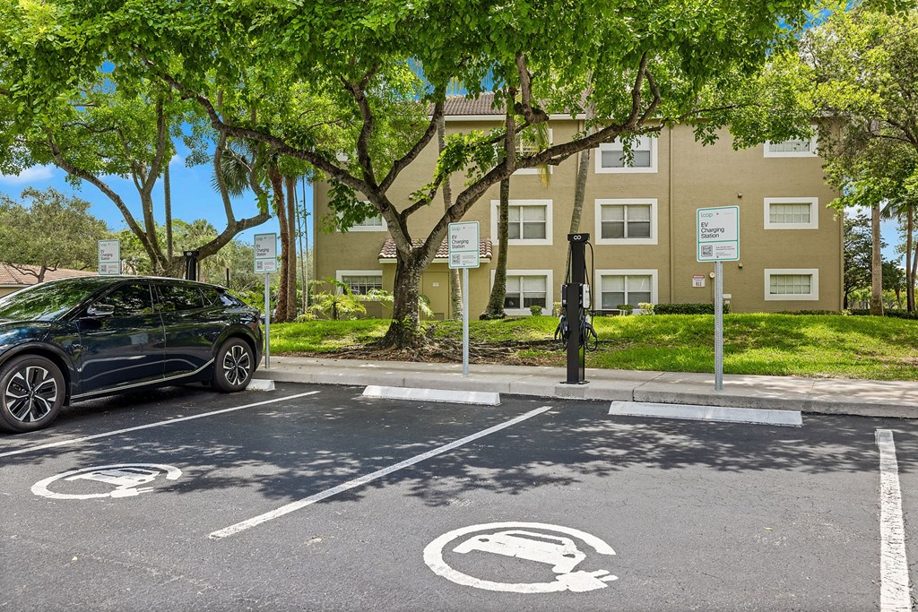 A black car is parked in a parking spot with a building in the background.