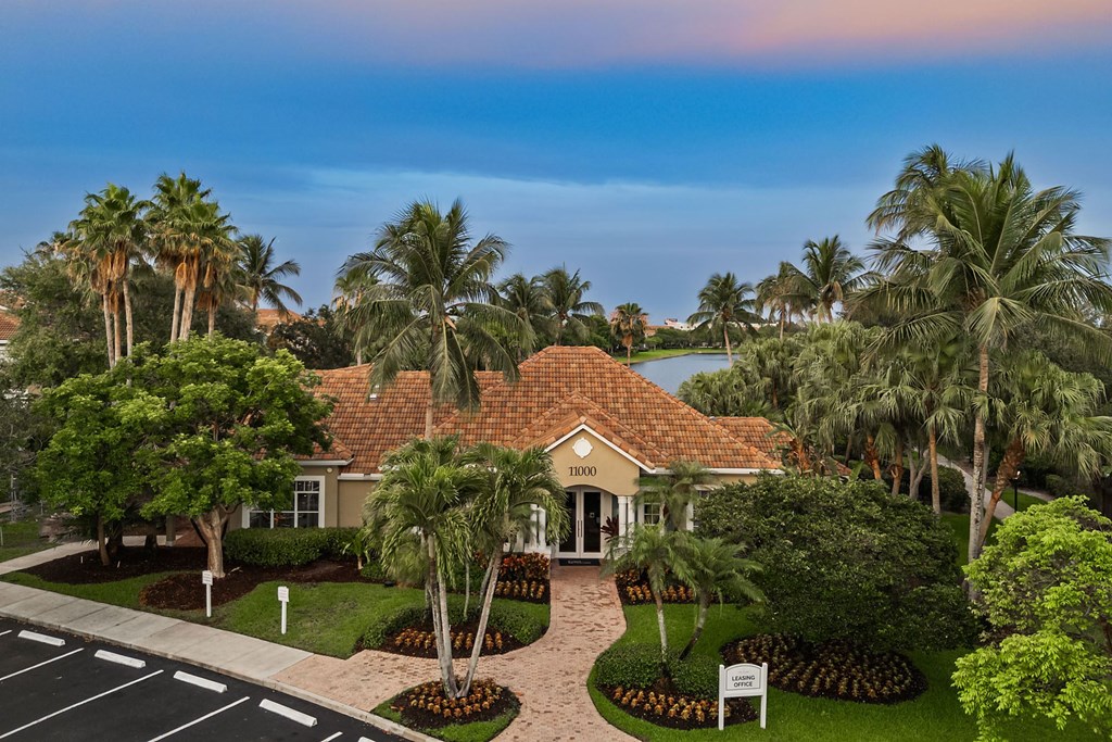A building surrounded by palm trees and water in the background.