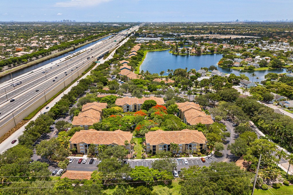 Many buildings surrounded by trees and a pond.