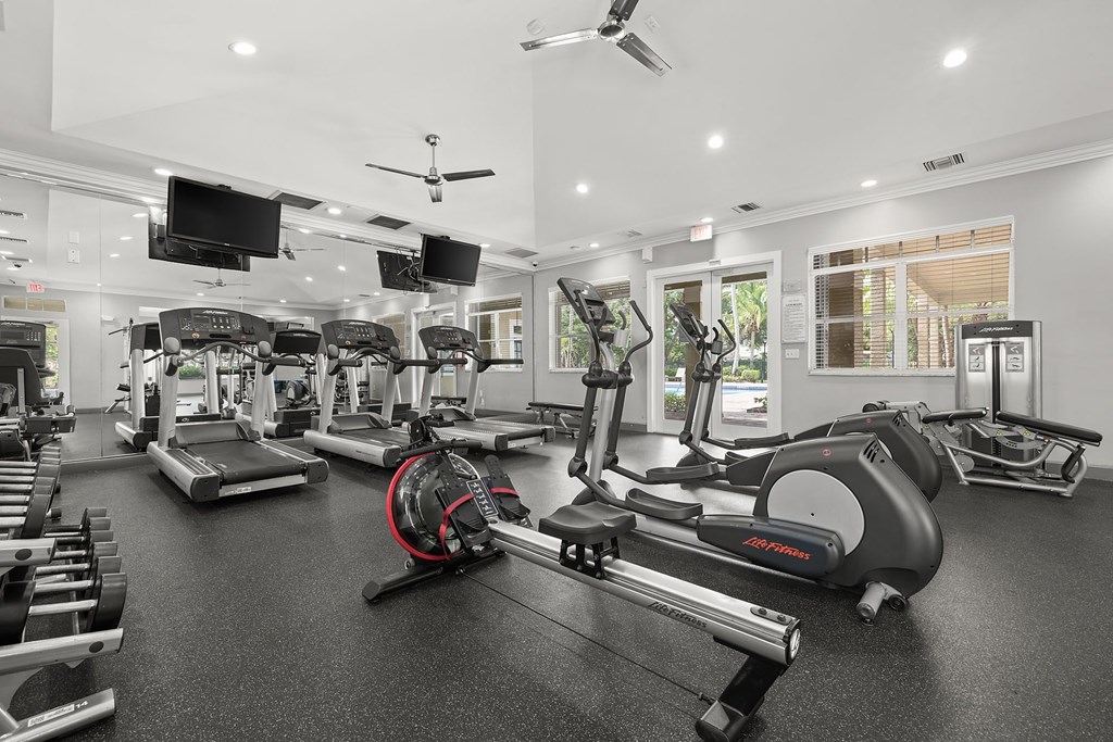 A gym with a variety of exercise equipment including treadmills, stationary bikes, and weight machines.