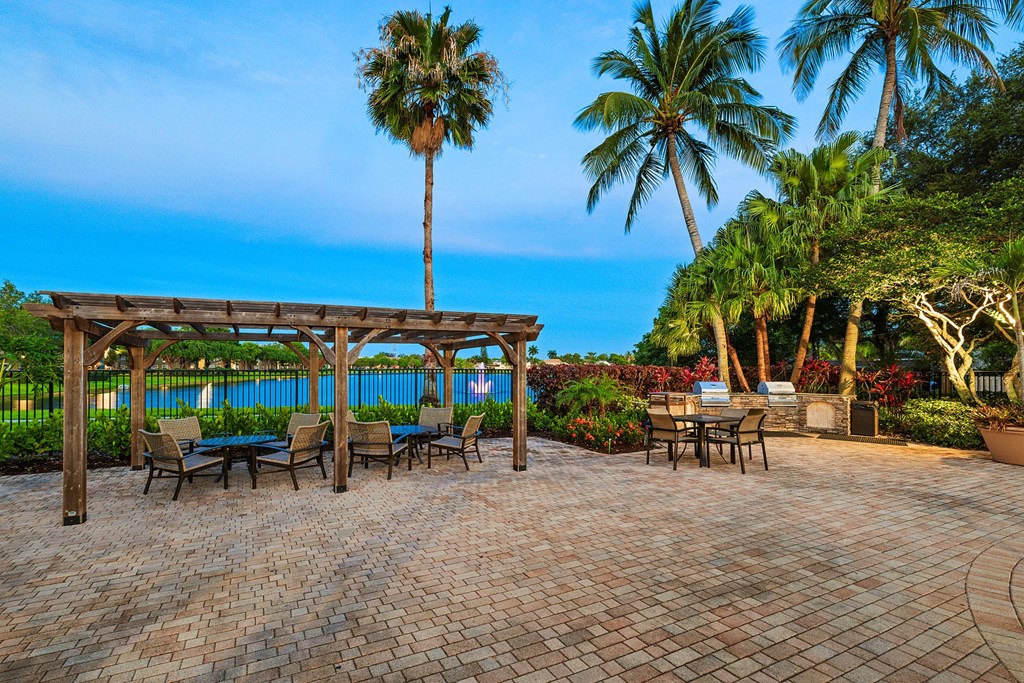 A patio with a table and chairs overlooking a pool.