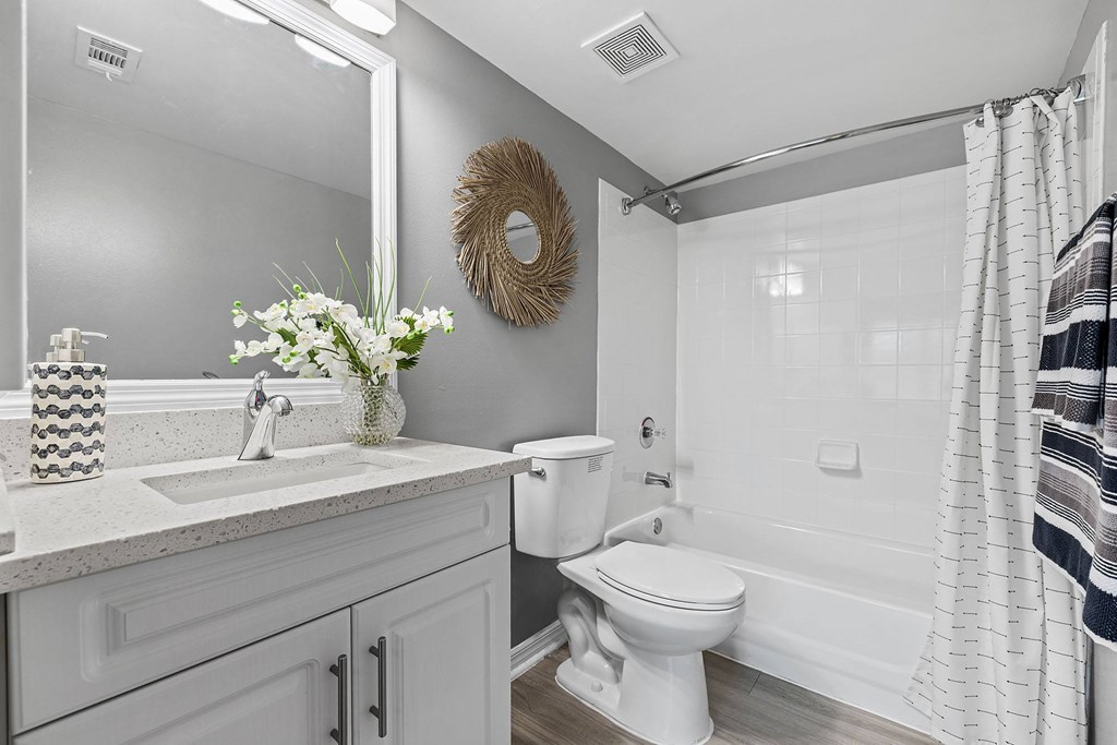 A white bathroom with a toilet, sink, and mirror.