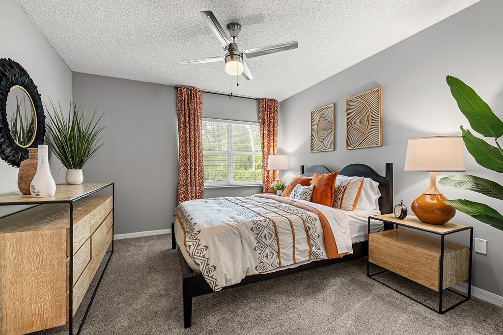 A bedroom with a bed, nightstand, and a ceiling fan.