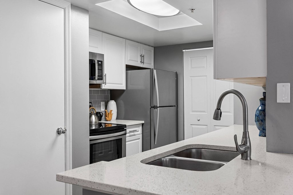 A modern kitchen with a stainless steel refrigerator and a white countertop.