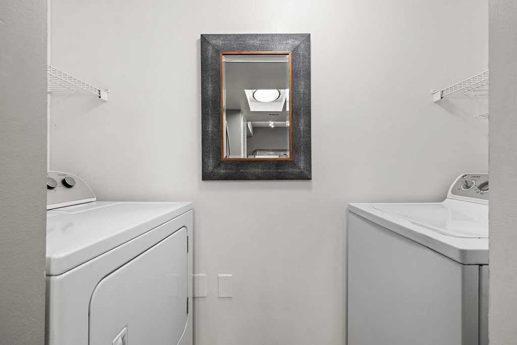 A white washer & dryer and a mirror on the wall.