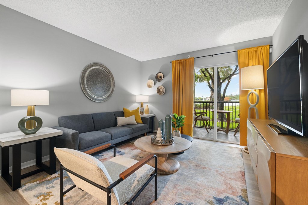 A living room with a grey couch, a coffee table, and a flat screen TV.