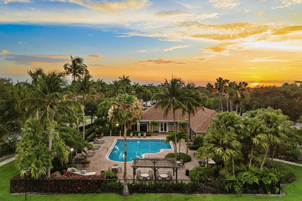 A building with a pool surrounded by palm trees.