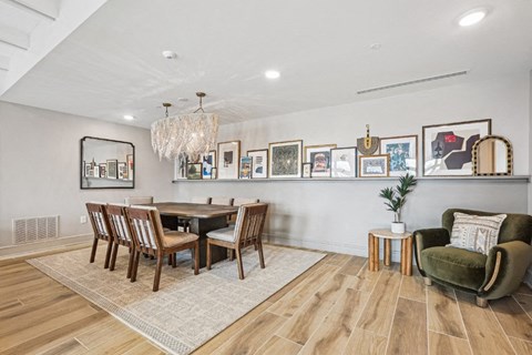A wooden table and chairs around it with picture frames on the wall.