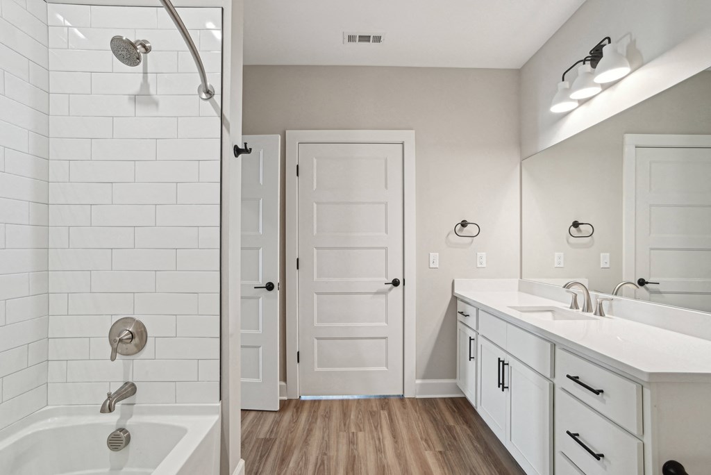 a white bathroom with a tub and a sink and a shower