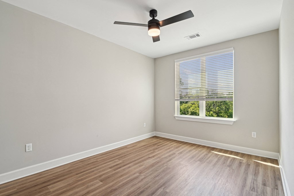 an empty room with a ceiling fan and a window