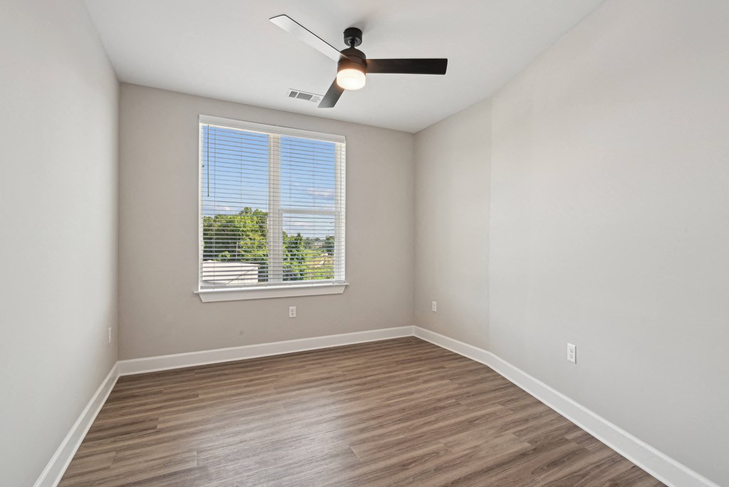 an empty room with a ceiling fan and a window
