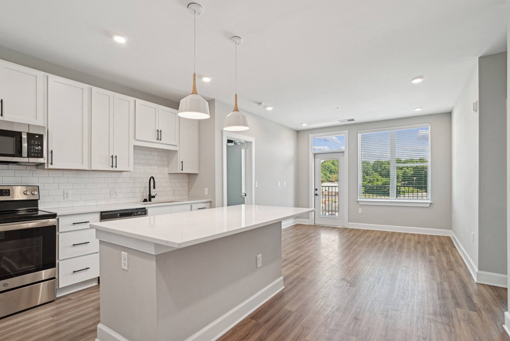 an open kitchen and living room with white cabinets and a white counter top