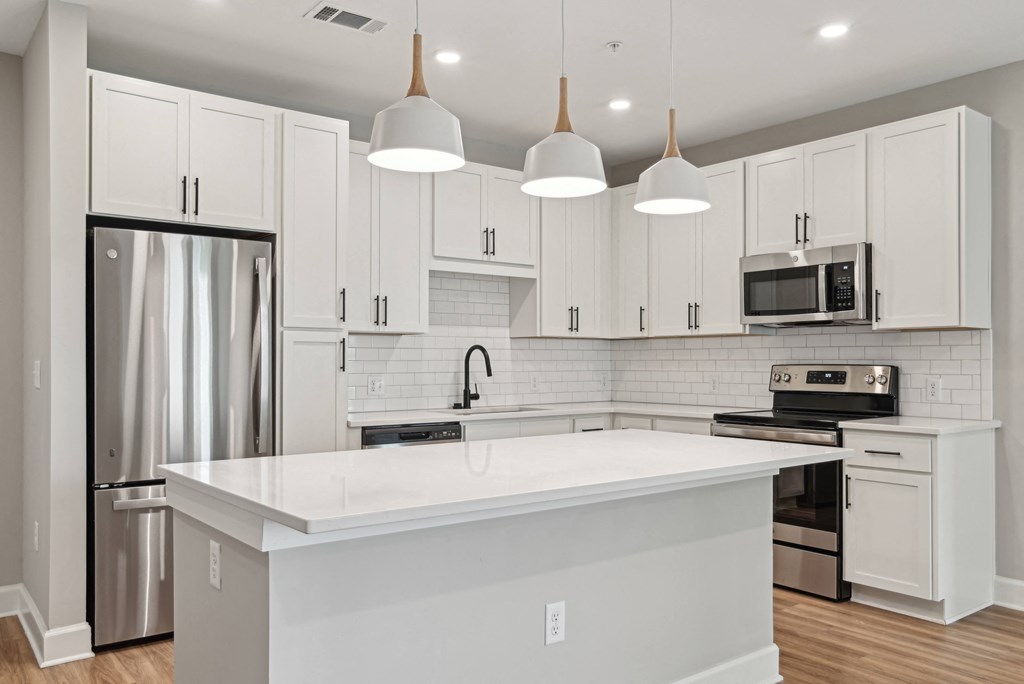 a large white kitchen with white cabinets and stainless steel appliances