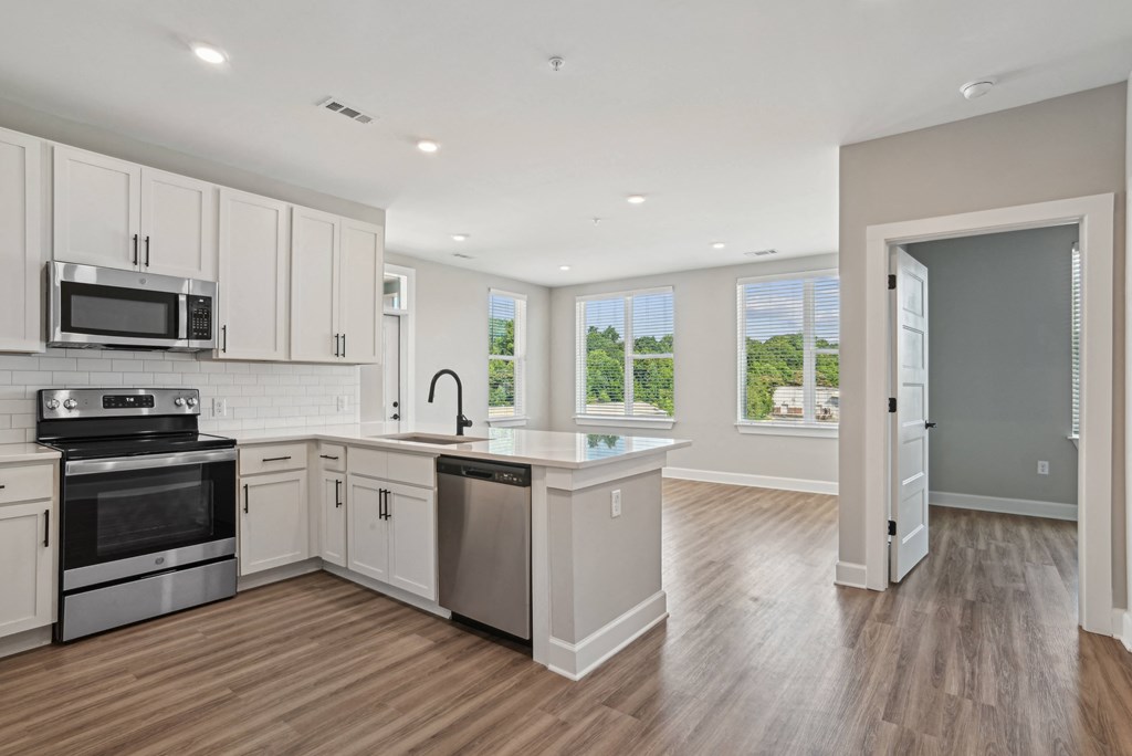 an empty kitchen with white cabinets and stainless steel appliances