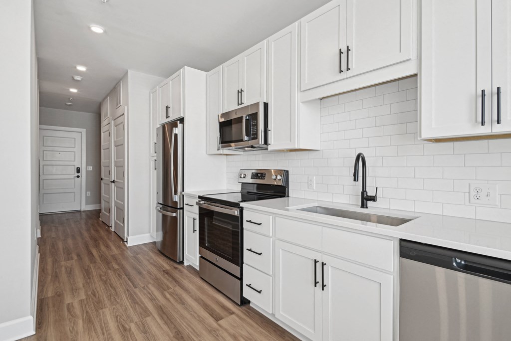 a renovated kitchen with white cabinets and stainless steel appliances
