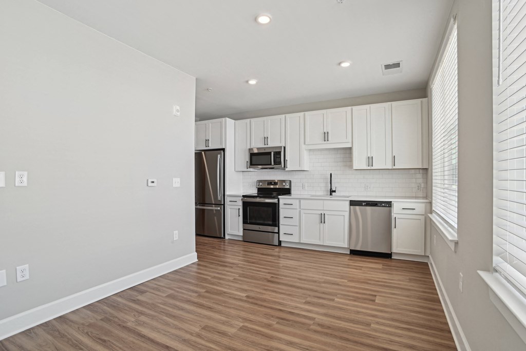 an empty kitchen with white cabinets and stainless steel appliances