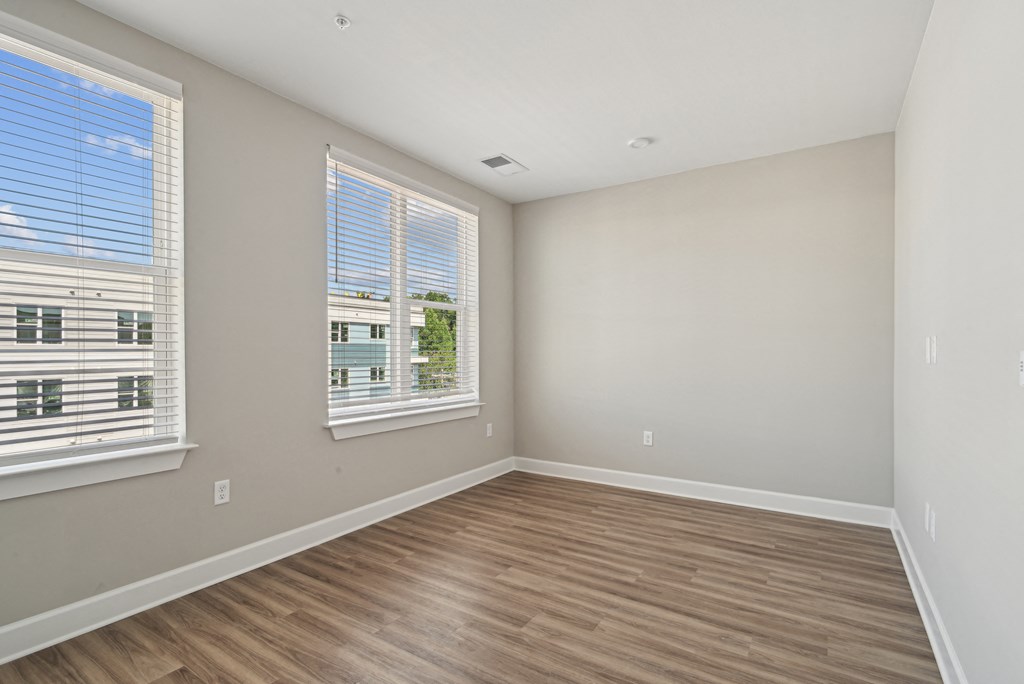 an empty living room with wood floors and two windows