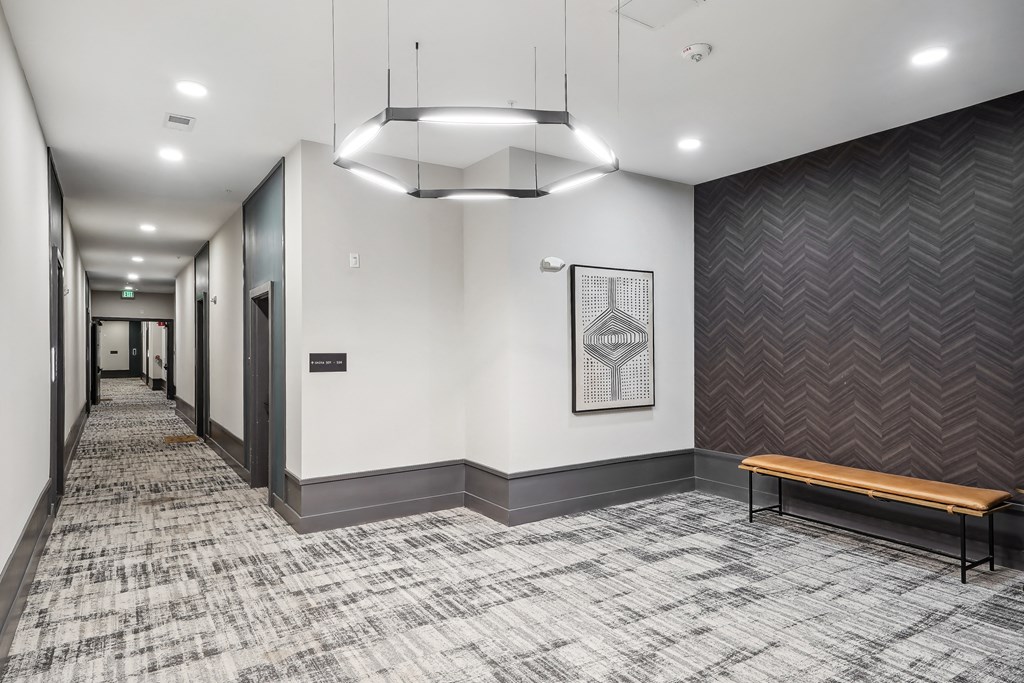 an empty hallway with a bench and a chandelier
