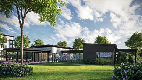 A modern building with a large glass window and a green lawn in front.