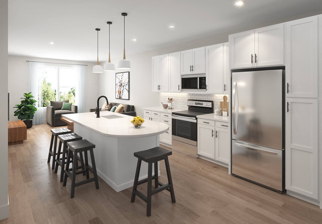 a white kitchen with a large island and a stainless steel refrigerator