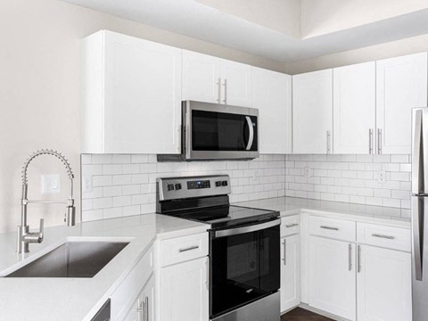 a white kitchen with black appliances and white cabinets