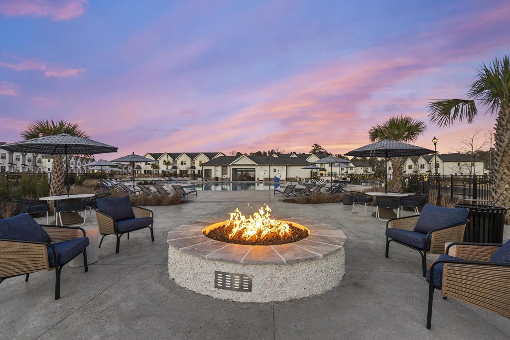 A fire pit sits in the middle of a patio surrounded by chairs.