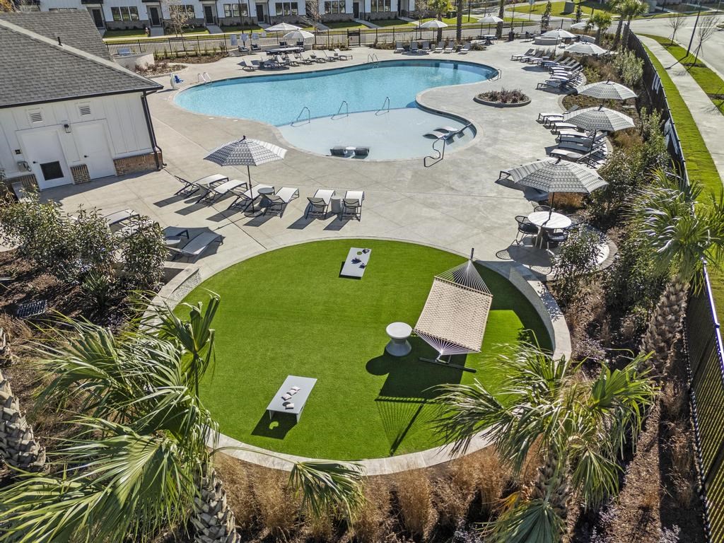 A large outdoor swimming pool with a grassy activity lawn in front of it.