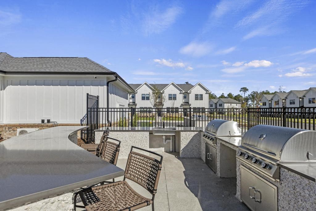 A patio with a table and chairs is surrounded by a black fence.