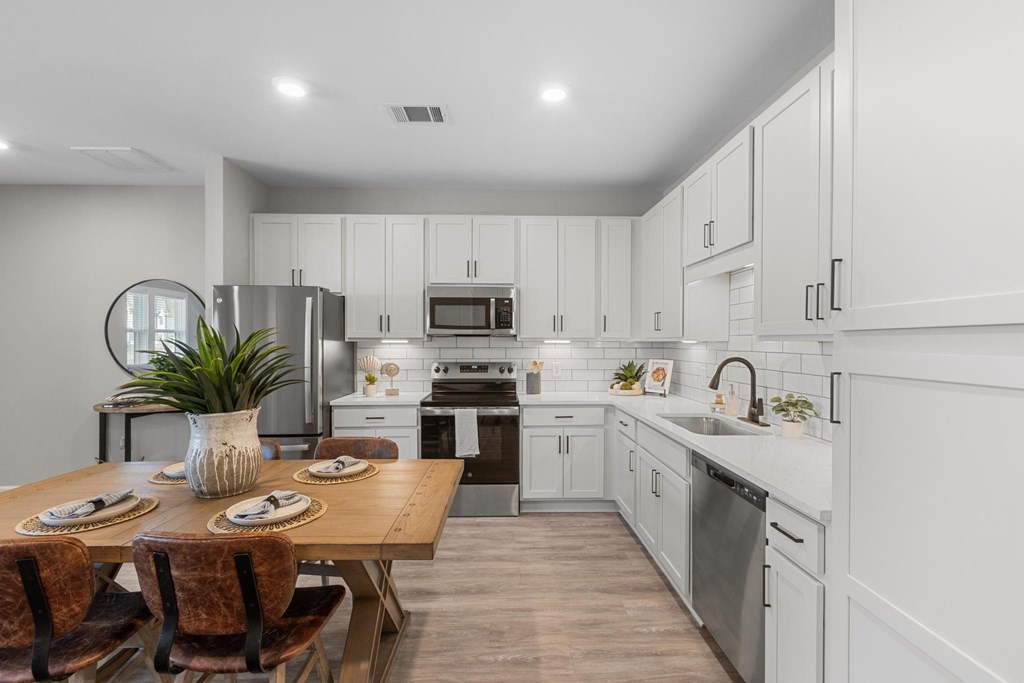 A modern kitchen with a dining table set for two.