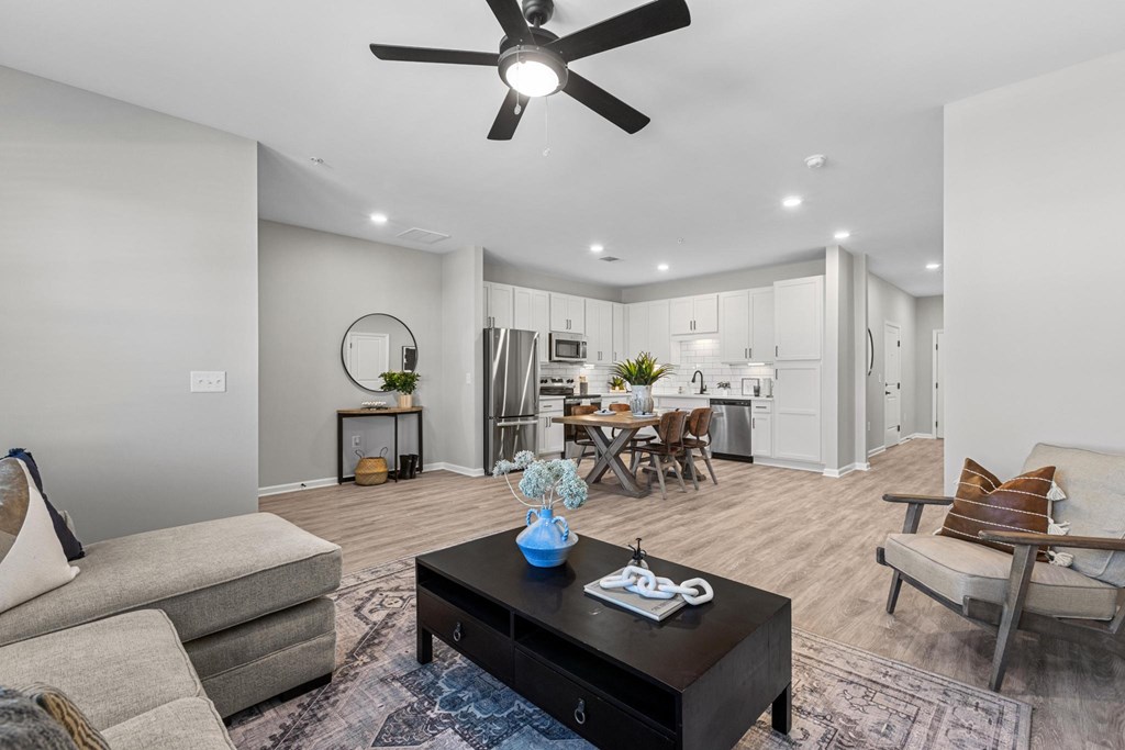 A modern living room with a grey sofa, a black coffee table, and a ceiling fan.
