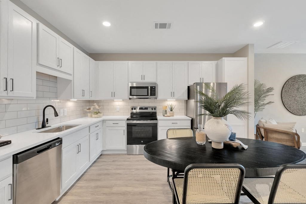 a kitchen with white cabinets and a black table