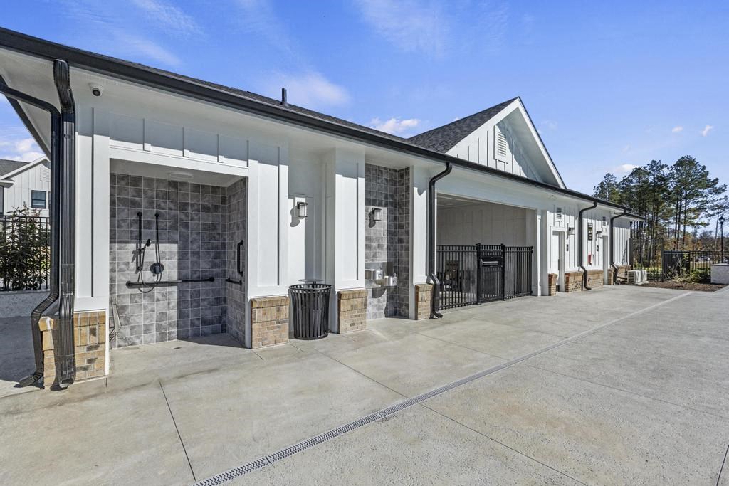 A white building with a black roof and showers.