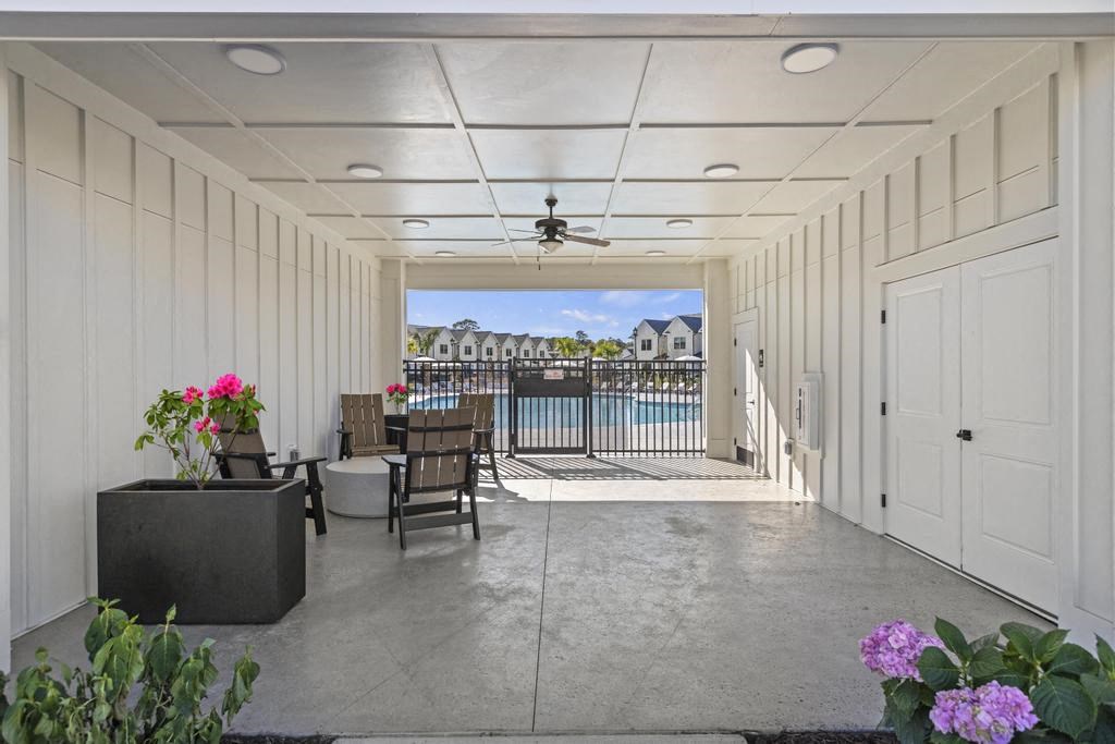 A patio with a table and chairs overlooking a pool.