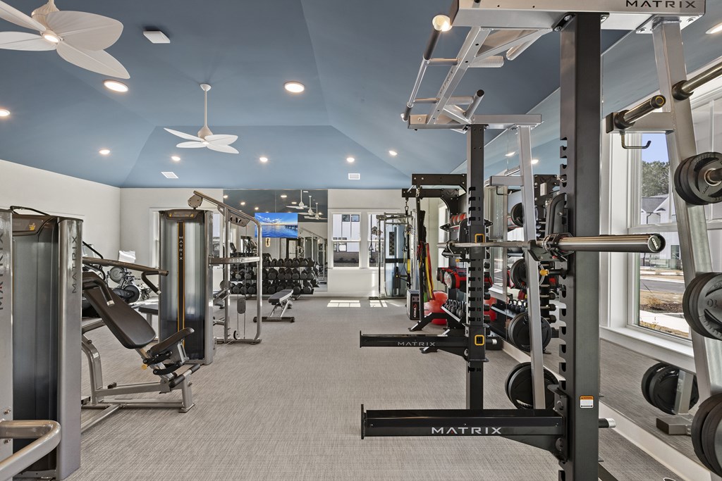 A gym with a variety of equipment including a treadmill weights and a smith machine.