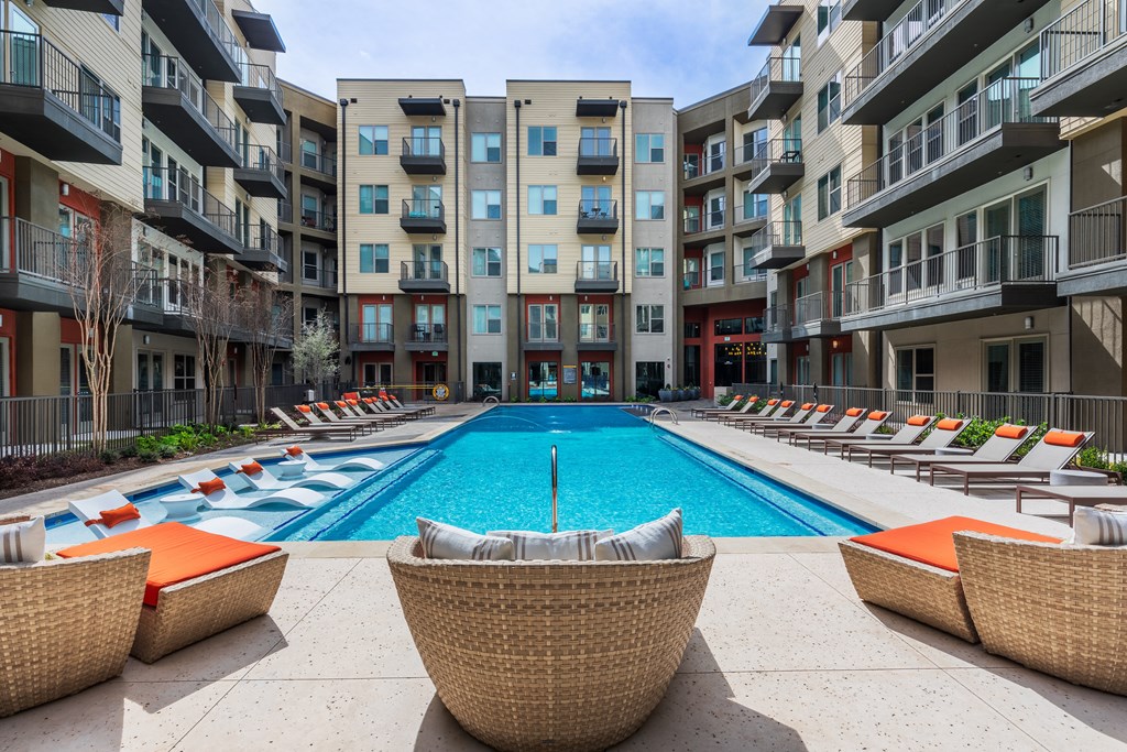 a swimming pool with lounge chairs in front of an apartment building