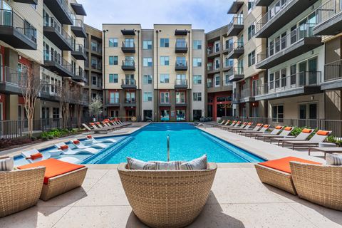 a swimming pool with lounge chairs in front of an apartment building