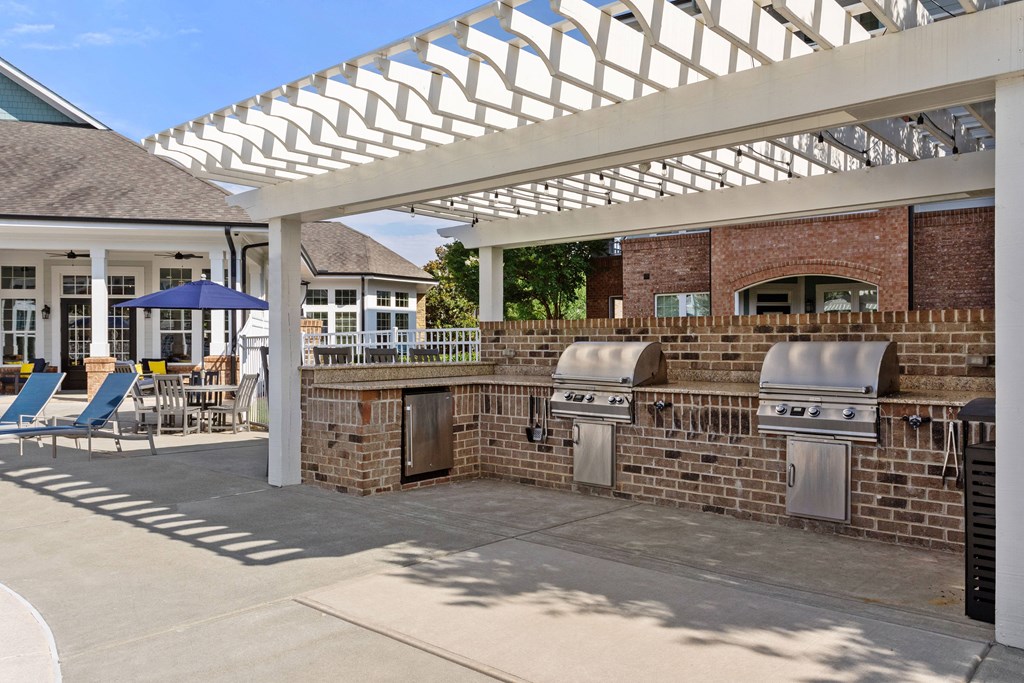 a pergola with two bbq grills in front of a house