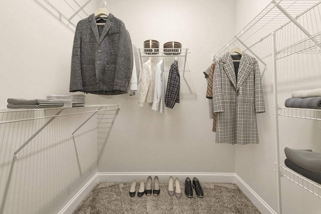 A walk in closet with a variety of coats and shoes.